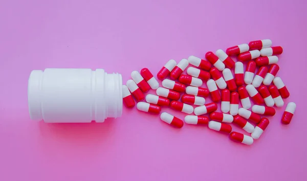 药丸胶囊从药丸瓶中溢出 并被粉红色隔离 具有复制空间的顶部视图 医药药学药理学健康观 — 图库照片