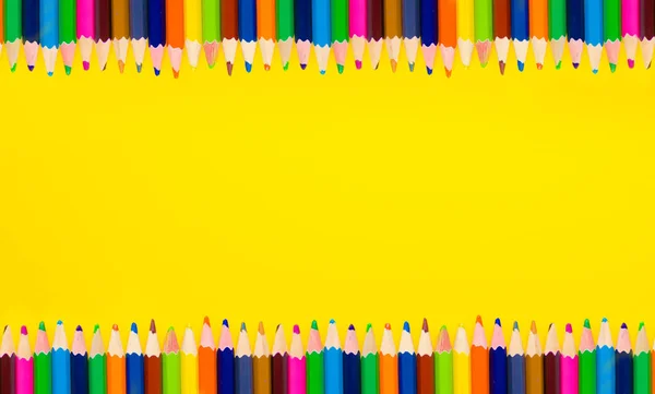 Sarı bir arka plan üzerinde renkli kalemler çerçevesinde