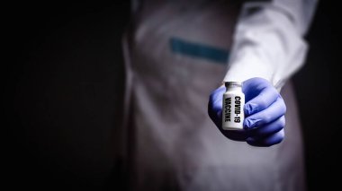 Coronavirus aşısı doktoru elinde, kovid-19 hastalığının adını kopyalamak için bir şırınga tutuyor. Tıbbi eldiven konsepti. Bilimsel çalışmalar bir hastalığın gelişimi ve tedavisi veya salgın hastalığın tedavisi.