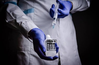 Coronavirus aşısı doktoru elinde, kovid-19 hastalığının adını kopyalamak için bir şırınga tutuyor. Tıbbi eldiven konsepti. Bilimsel çalışmalar bir hastalığın gelişimi ve tedavisi veya salgın hastalığın tedavisi.