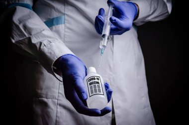 Coronavirus aşısı doktoru elinde, kovid-19 hastalığının adını kopyalamak için bir şırınga tutuyor. Tıbbi eldiven konsepti. Bilimsel çalışmalar bir hastalığın gelişimi ve tedavisi veya salgın hastalığın tedavisi.