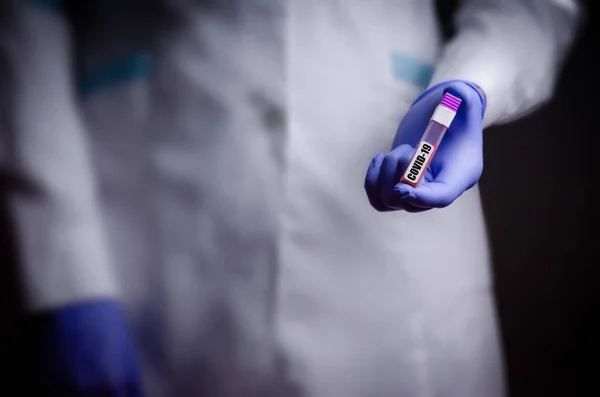 Doktorun elinde bir koronavirüs var. Salgın virüsünün tedavisinde kullanılan Covid-19 tıp eldiveni konseptini içeren bir kan testi.