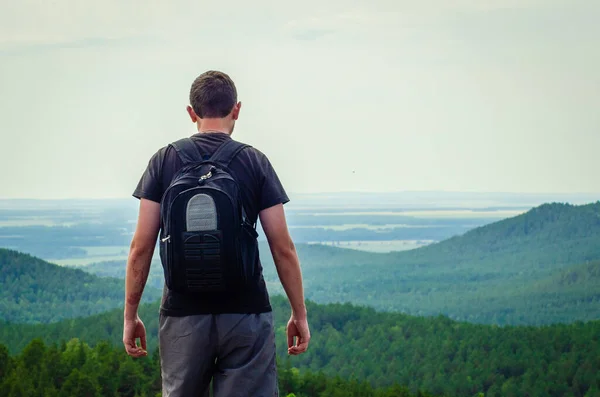 stock image young man with backpack standing on the mountain top  