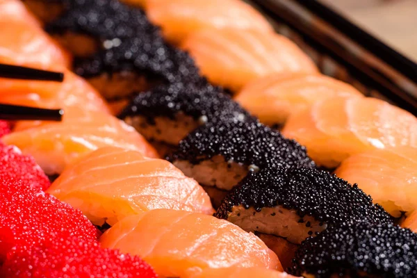 Różne rodzaje sushi serwowane na ciemnym tle — Zdjęcie stockowe