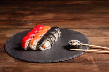 Karanlık bir arka planda servis edilen çeşitli suşi çeşitleri.