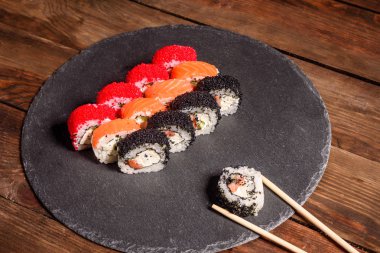 Karanlık bir arka planda servis edilen çeşitli suşi çeşitleri.