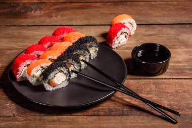 Karanlık bir arka planda servis edilen çeşitli suşi çeşitleri.