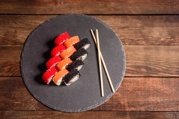 Verschiedene Arten von Sushi auf dunklem Hintergrund serviert — Stockfoto