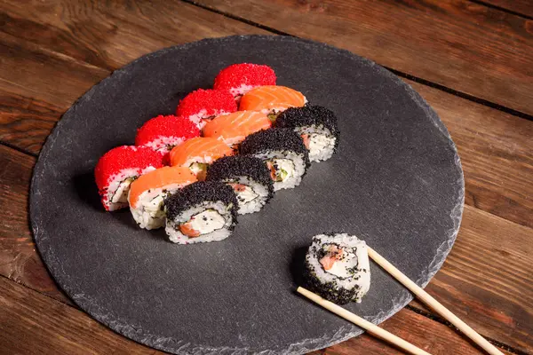 Verschiedene Arten von Sushi auf dunklem Hintergrund serviert — Stockfoto