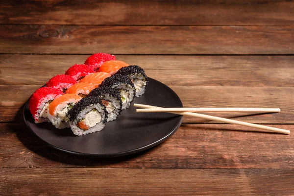 Różne rodzaje sushi serwowane na ciemnym tle — Zdjęcie stockowe