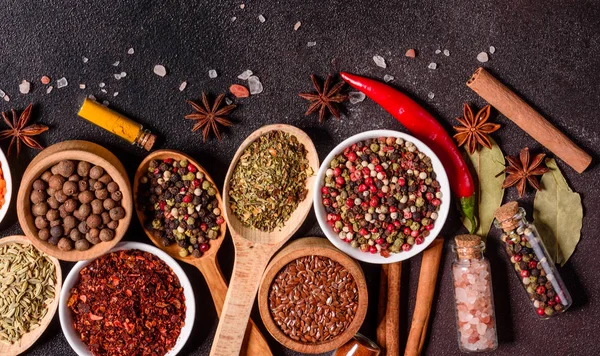 Een set kruiden en specerijen. Indiase keuken. Peper, zout, paprika, basilicum en andere op een donkere achtergrond — Stockfoto