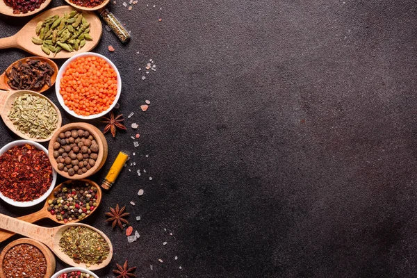 Um conjunto de especiarias e ervas. Cozinha indiana. Pimenta, sal, páprica, manjericão e outros em um fundo escuro — Fotografia de Stock