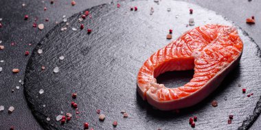 Çiğ alabalık, kırmızı balık bifteği, otlar, limon ve koyu bir arka planda zeytinyağı ile servis edilir.