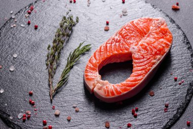 Çiğ alabalık, kırmızı balık bifteği, otlar, limon ve koyu bir arka planda zeytinyağı ile servis edilir.