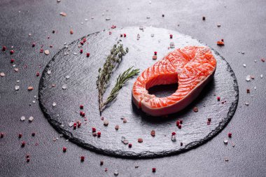 Çiğ alabalık, kırmızı balık bifteği, otlar, limon ve koyu bir arka planda zeytinyağı ile servis edilir.