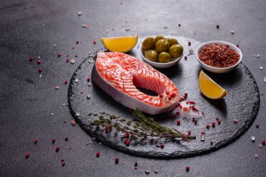 Çiğ alabalık, kırmızı balık bifteği, otlar, limon ve koyu bir arka planda zeytinyağı ile servis edilir.