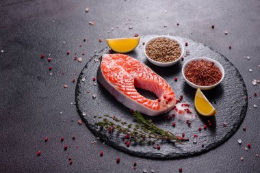 Çiğ alabalık, kırmızı balık bifteği, otlar, limon ve koyu bir arka planda zeytinyağı ile servis edilir.