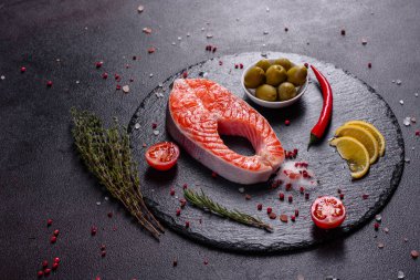 Çiğ alabalık, kırmızı balık bifteği, otlar, limon ve koyu bir arka planda zeytinyağı ile servis edilir.