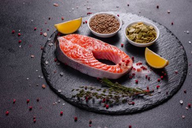 Çiğ alabalık, kırmızı balık bifteği, otlar, limon ve koyu bir arka planda zeytinyağı ile servis edilir.