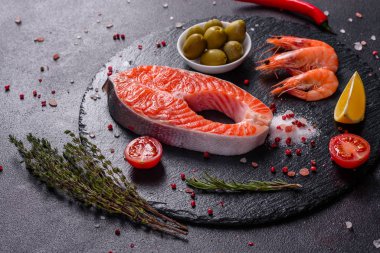 Çiğ alabalık, kırmızı balık bifteği, otlar, limon ve koyu bir arka planda zeytinyağı ile servis edilir.