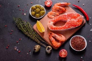 Çiğ alabalık, kırmızı balık bifteği, otlar, limon ve koyu bir arka planda zeytinyağı ile servis edilir.