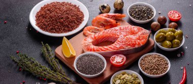 Çiğ alabalık, kırmızı balık bifteği, otlar, limon ve koyu bir arka planda zeytinyağı ile servis edilir.