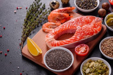 Çiğ alabalık, kırmızı balık bifteği, otlar, limon ve koyu bir arka planda zeytinyağı ile servis edilir.