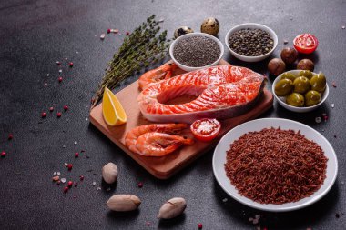 Çiğ alabalık, kırmızı balık bifteği, otlar, limon ve koyu bir arka planda zeytinyağı ile servis edilir.