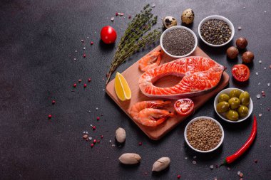 Çiğ alabalık, kırmızı balık bifteği, otlar, limon ve koyu bir arka planda zeytinyağı ile servis edilir.