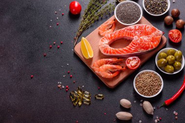 Çiğ alabalık, kırmızı balık bifteği, otlar, limon ve koyu bir arka planda zeytinyağı ile servis edilir.