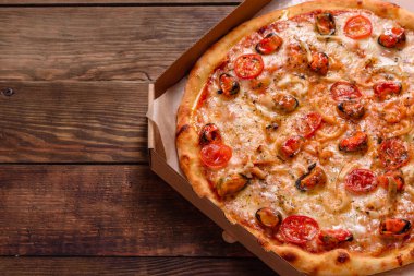 Beton zeminde deniz ürünleri ve domatesli dilimlenmiş pizza.