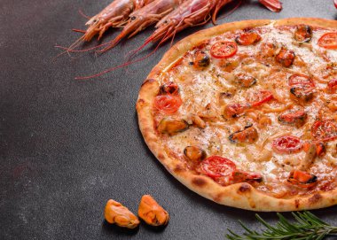 Beton zeminde deniz ürünleri ve domatesli dilimlenmiş pizza.