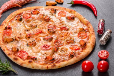 Beton zeminde deniz ürünleri ve domatesli dilimlenmiş pizza.