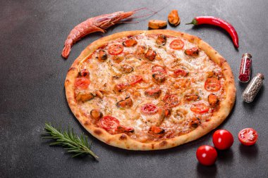 Beton zeminde deniz ürünleri ve domatesli dilimlenmiş pizza.