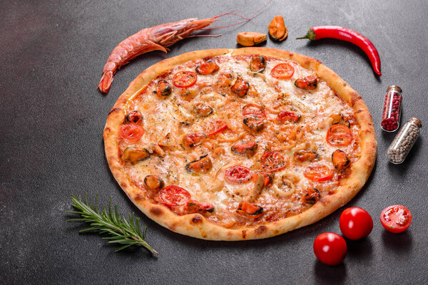 Tasty sliced pizza with seafood and tomato on a concrete background