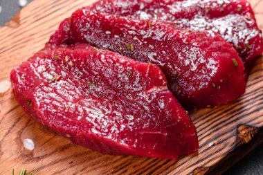 Taze çiğ biftek Mignon, tuzlu, biberli, kekik ve domatesli. Çiğ mermer et Biftek ve koyu bir arka planda baharatlar