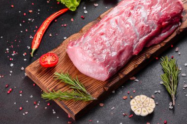 Mutfaktaki koyu bir arka planda pişmeye hazır taze domuz parçaları. Sığır filetosu madalyonları pişmeye hazır.