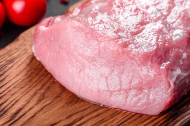 Mutfaktaki koyu bir arka planda pişmeye hazır taze domuz parçaları. Sığır filetosu madalyonları pişmeye hazır.