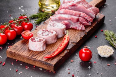 Mutfaktaki koyu bir arka planda pişmeye hazır taze domuz parçaları. Sığır filetosu madalyonları pişmeye hazır.