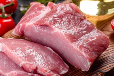 Mutfaktaki koyu bir arka planda pişmeye hazır taze domuz parçaları. Sığır filetosu madalyonları pişmeye hazır.