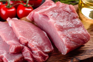 Mutfaktaki koyu bir arka planda pişmeye hazır taze domuz parçaları. Sığır filetosu madalyonları pişmeye hazır.