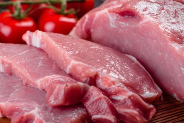 Mutfaktaki koyu bir arka planda pişmeye hazır taze domuz parçaları. Sığır filetosu madalyonları pişmeye hazır.