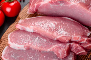 Mutfaktaki koyu bir arka planda pişmeye hazır taze domuz parçaları. Sığır filetosu madalyonları pişmeye hazır.