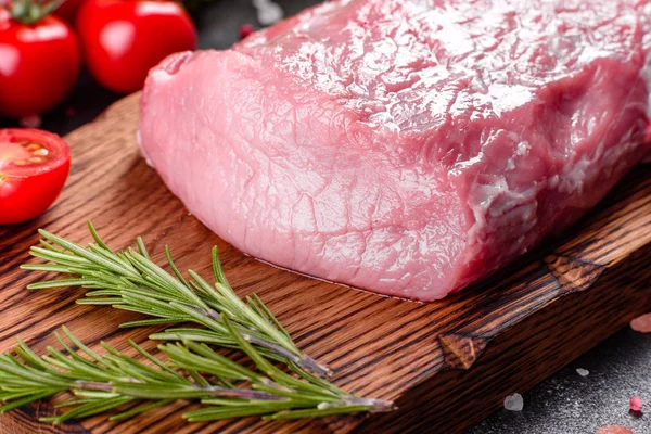 Mutfaktaki koyu bir arka planda pişmeye hazır taze domuz parçaları. Sığır filetosu madalyonları pişmeye hazır.