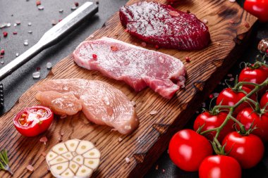 Etli taze biftek, domuz eti ve sebzeli tavuk pişmeye hazır. Farklı et çeşitlerinden biftekler pişirmek için hazırlandı.