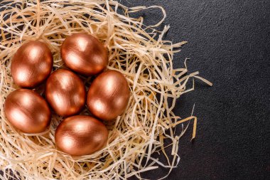Yuvadaki Paskalya altın yumurtaları, bayram hazırlıkları. Koyu renkli arka planda yuvadaki altın yumurtalar.