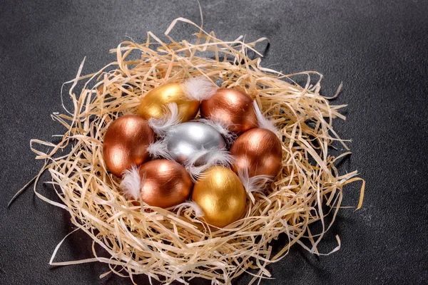 Easter golden eggs in the nest, preparation for the holiday. Golden eggs in nest on dark vintage background.