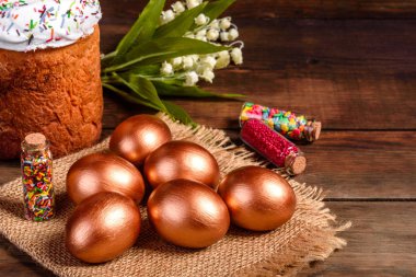 Paskalya yumurtası, altın, bronz ve arka planda Paskalya pastası. Tatil için hazırlık