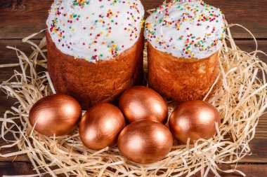 Yuvadaki Paskalya altın yumurtaları, bayram hazırlıkları. Koyu renkli arka planda yuvadaki altın yumurtalar.