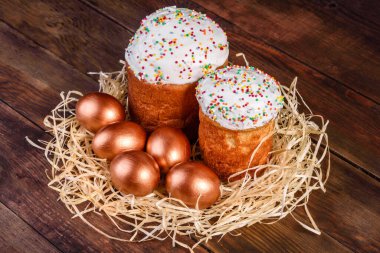 Yuvadaki Paskalya altın yumurtaları, bayram hazırlıkları. Koyu renkli arka planda yuvadaki altın yumurtalar.